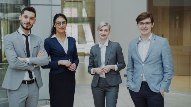 Four business professionals posing confidently in a modern office environment. Four business professionals posing confidently in a modern office environment.